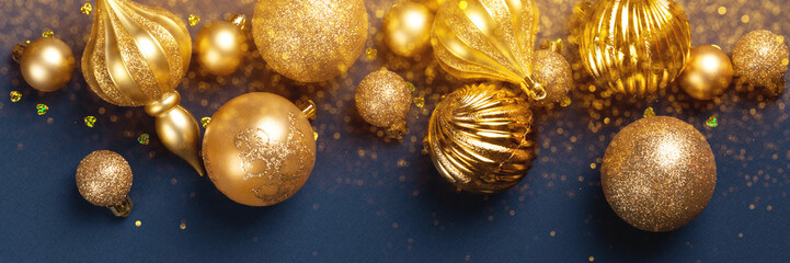 Christmas banner with golden glitter balls and toys on blue background. Wide panoramic header