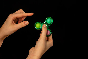 Child's hand playing with a fidget spinner toy - obrazy, fototapety, plakaty