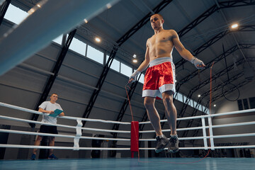 Jumping rope. Young sportive man, boxer workout at boxing ring at sports gym. Health, motivation...