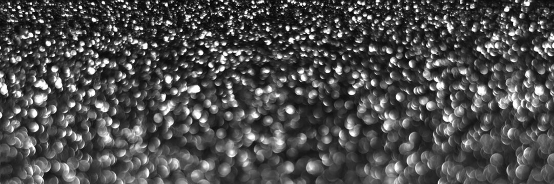 Gray black sparkling glitter bokeh background, christmas abstract defocused texture. Holiday lights. Snowy shiny sparkle stars header. Wide screen wallpaper. Panoramic web banner with copy space © MariiaDemchenko