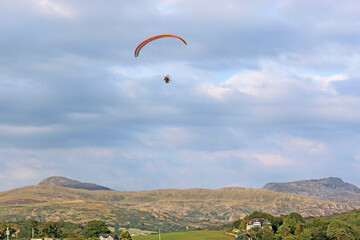 Paramotor pilot flying in the hills of Wales	