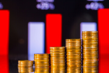 Stacks of golden coins on the background of a blurred business financial graph. Digital business and stock market financial indicator.