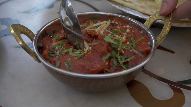 Butter paneer masala with hands closeup. Cottage cheese curry, hot spicy chicken korma, traditional indian food in in the restaurant