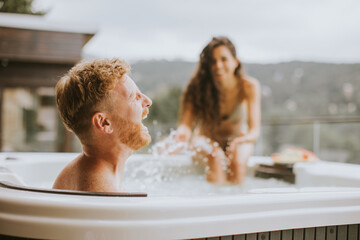 Young couple enjoying in outdoor hot tub on vacation
