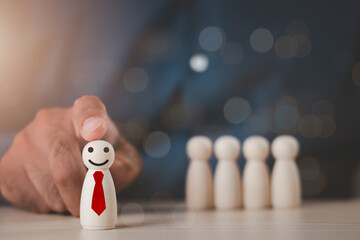 A wooden figure with a smiling face was chosen by a businessman. The concept of choosing leaders for business success. Organization development. Leadership. Personnel selection. Wooden puppet.