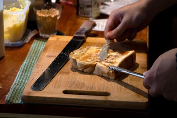 Spreading fresh butter on toasted on counter kitchen with warm light.