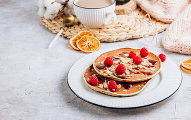 Fresh homemade pancakes with almonds, raspberry and coffee on white kithen background. Cozy breakfast