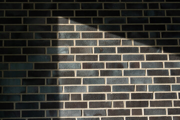 Wand aus dunklem Backstein mit Schatten