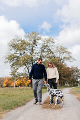 A loving couple plays with a Dalmatian dog on the street.