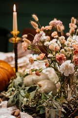 Autumn Decoration and serving of the festive table with autumn decor, candles and flowers and pumpkins.