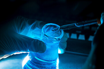 Blue science experiment glass tube,Researchers with chemistry test tubes in a liquid glass lab for...
