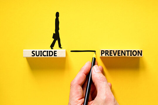 Suicide prevention symbol. Concept words Suicide prevention on wooden blocks. Beautiful yellow table yellow background. Psychologist hand. Psychological and suicide prevention concept. Copy space.