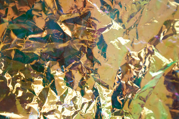 Holographic colored wrinkled yellow foil. Holographic texture of real fabric in yellow tones. Holographic Colorful plastic Film. High quality photo