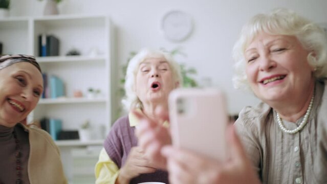Closeup of cheerful women in their 60s taking selfie on smartphone, having fun