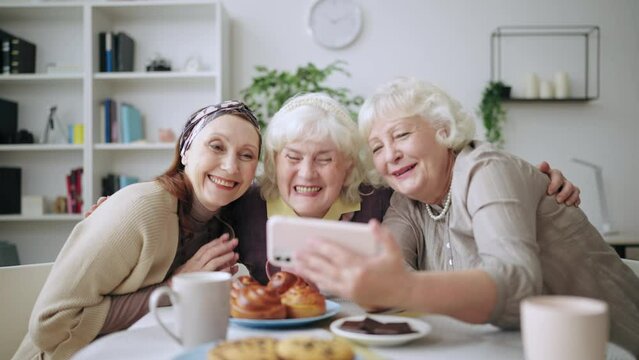 Happy elderly women taking selfie on smartphone, grandmas meeting for coffee