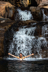 Fototapeta na wymiar a beautiful girl in a white bikini swims in a natural pool in jourama falls; relaxing in paluma range national park in queensland, australia; cascading waterfalls with pools