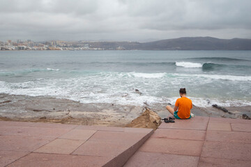 Hombre meditando solo frente al mar.