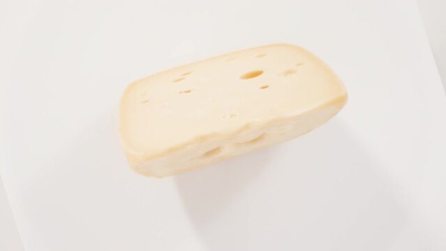 Flat lay. Large slice of semi soft part skim cheese on a white background.