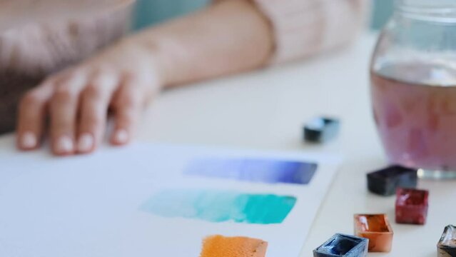 Talented girl doing simple execrises with watercolor paint in the art class