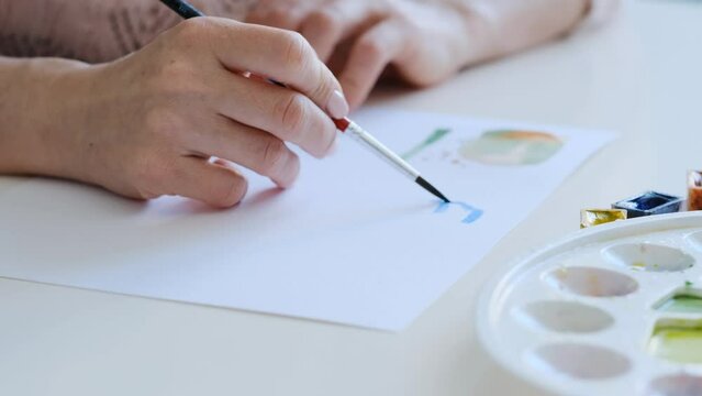 Talented girl doing simple execrises with watercolor paint in the art class
