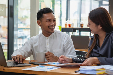 Business men and women sitting looking at each other with coffee cups and talking in the company.