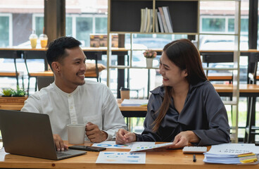 Business men and women sitting looking at each other with coffee cups and talking in the company.