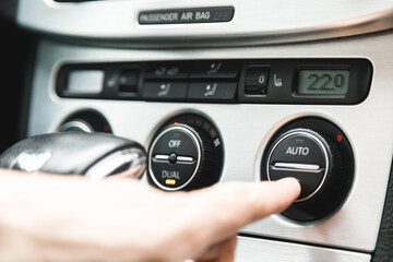 Fototapeta premium Hand Presses the Button to Turn on the Air Conditioning in the Car