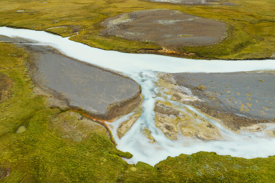 Aerial top view of river Sanda between grasslands in the highlands of Iceland.