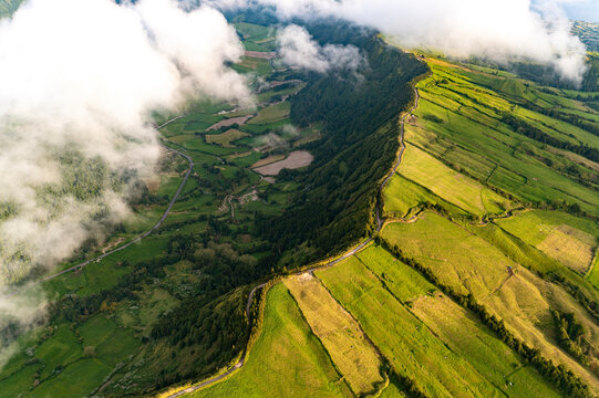 Aerial view of the rim of a crater with clouds and fields, Sao Miguel, Azores, Portugal.