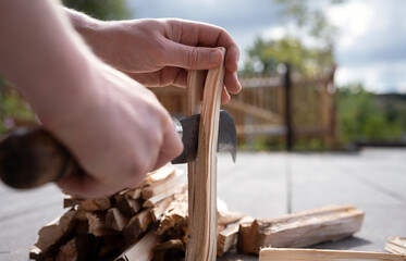 Close-up of hands and an old, rusty knife chopping wood for lighting the fireplace