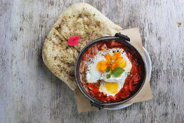 Shakshuka with pita bread served in dish isolated on wooden background top view of breakfast