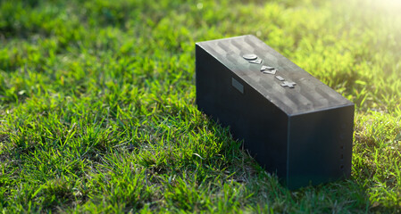 Rectangular mobile audio speaker on green grass. Listening to music in nature. Take music with you...