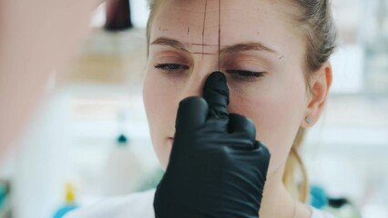 Permanent makeup master marks the lines with a special thread to create the correct shape of model eyebrows