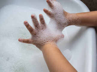 Fototapeta premium Child washing hand full of foam in bathroom sink