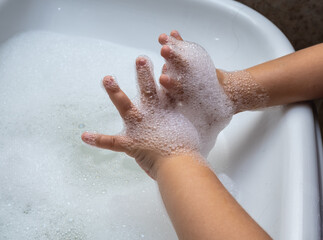 Fototapeta premium Child washing hand full of foam in bathroom sink