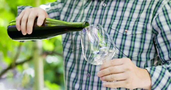 Male winemaker or sommelier is pouring red wine in glass