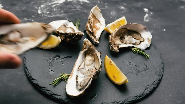 Woman and man hands take oysters from black platter with lemon