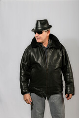 handsome elderly man with sunglasses, hat and black leather jacket