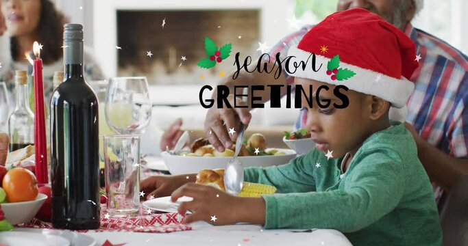 Animation of christmas greetings text over african american boy at christmas meal table