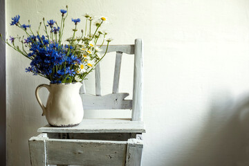 A bouquet of wild flowers of daisies and cornflowers in a rustic interior.