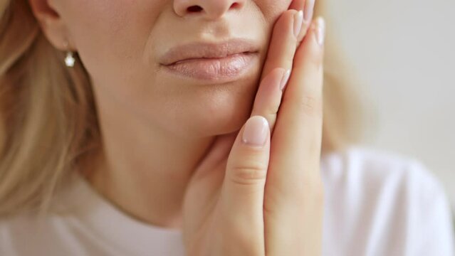 Woman with a toothache, touching her face. The concept of dental disease. Tooth pain due to caries