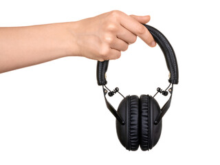 A woman's hand holds modern folding black headphones, with a leather headband. Isolated on white background.