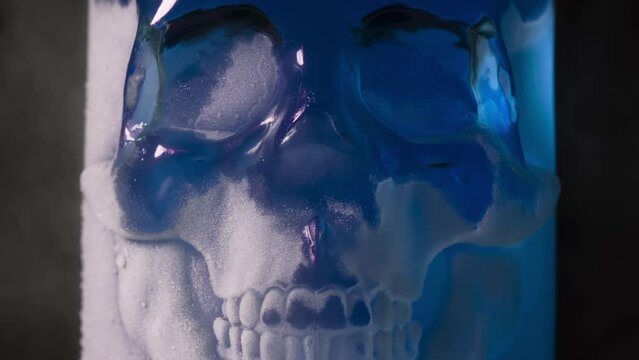Blue Glass Skull in Frost. A glass vessel with a bright, rich amethyst-blue content in the form of a glass skull, cooled by liquid evaporating nitrogen
