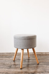 Trendy stool with build-in storage. Side view, white wall, space for