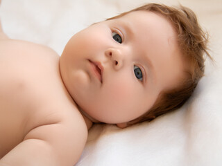 A healthy newborn baby lies on the bed and smiles. The concept of children's health and beauty. Happy Motherhood and Fatherhood