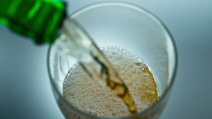 Alcohol liquid jet bubbling into transparent glass top view. Bottle pouring beer