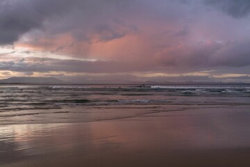 Beautiful soft pink sunset with fluffy clouds over the sea shore