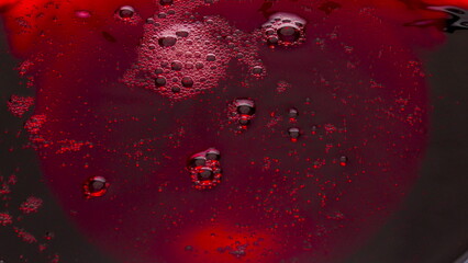 Red wine foamy texture closeup. Bubbled liquid surface frothing moving top view