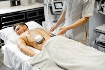 Obraz premium Man receiving vacuum roller massage on his back at medical beauty centre. Lymphatic drainage massage procedure