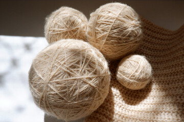 Wool balls of beige yarn for knitting and knitted thing.The concept of manual labor, crafts, hobbies, a banner for the sale of yarn.Copyspace.